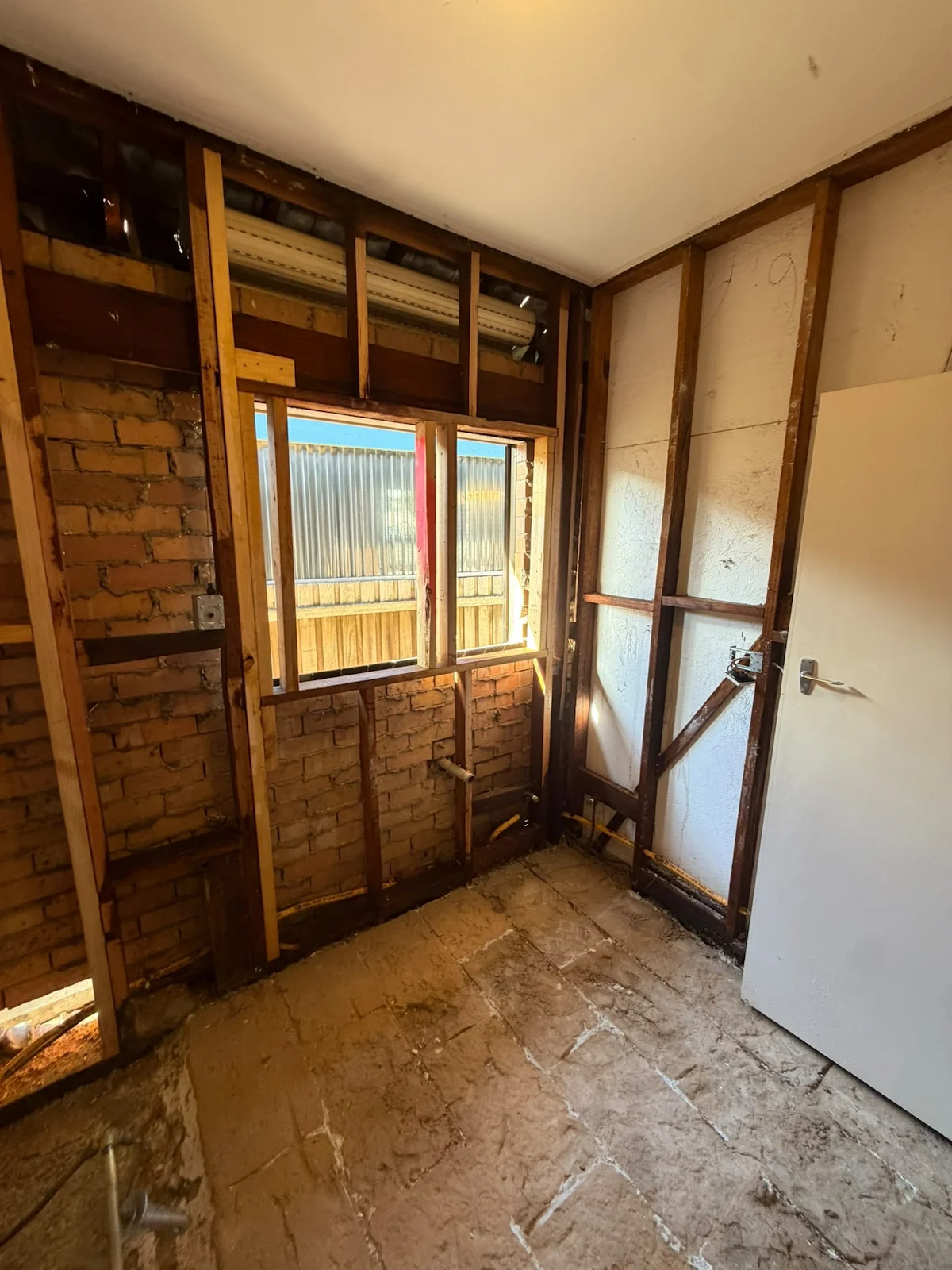 Stripped Fawkner bathroom showing the exposed concrete slab and timber framing